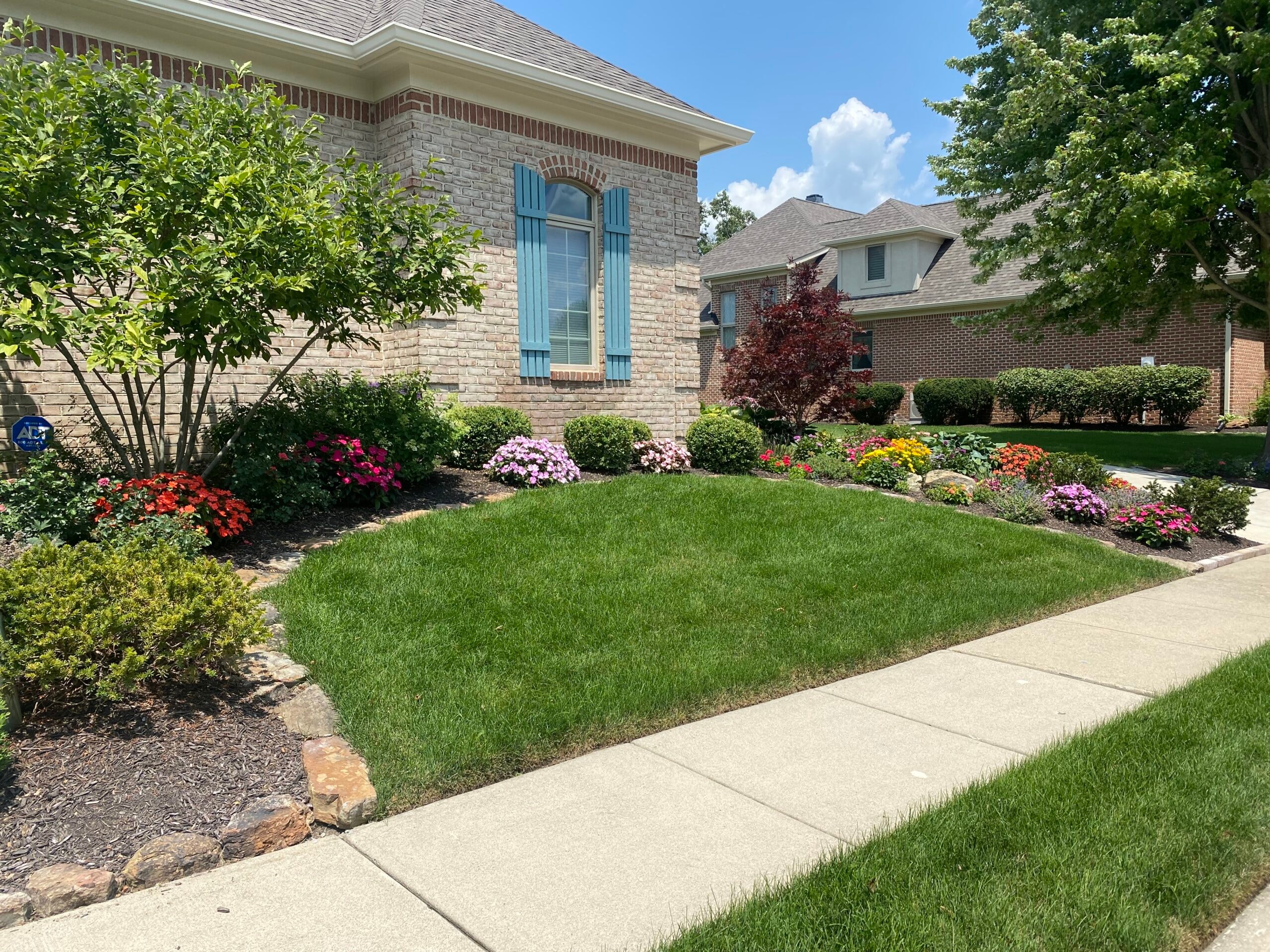 Residential lawn care brick home colorful flower garden